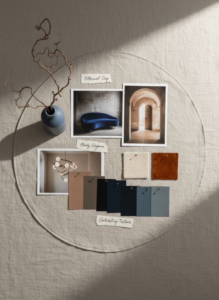 A curated moodboard for a “Bittersweet Shop” themed project laid out across a wide linen-covered table, featuring printed photos of moody yet elegant interiors, paint chips in warm taupes and inky blues, small samples of boucle and velvet, and photos of sculptural lighting fixtures. A single dried branch in a slim ceramic cylinder vase anchors one corner of the composition. Soft, overcast daylight enters from the right, producing a gentle, even wash of light with delicate shadows that highlight layered papers and textures. Photographic realism with a top-down composition and subtle vignetting creates a focused, professional atmosphere that communicates the brand’s curated aesthetic direction.